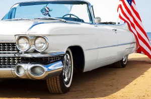 Classic white Cadillac at the beach with American flag